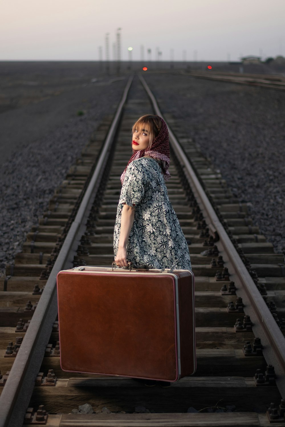 a woman standing on a train track with a suitcase