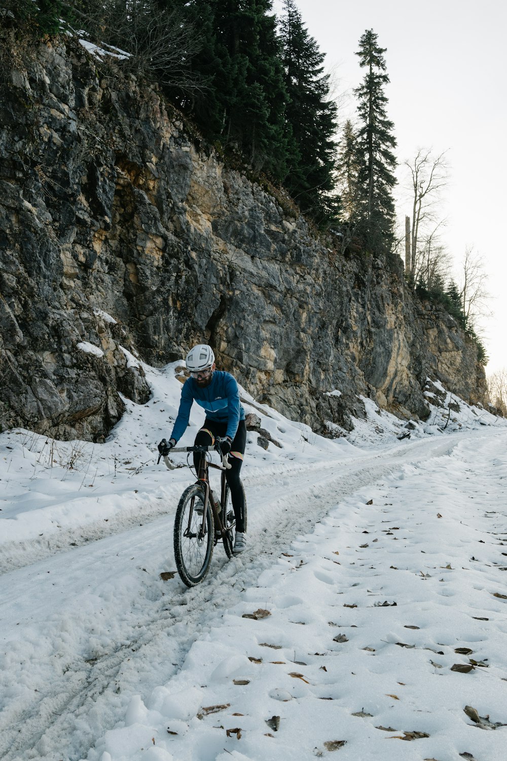 a man riding a bike down a snow covered road