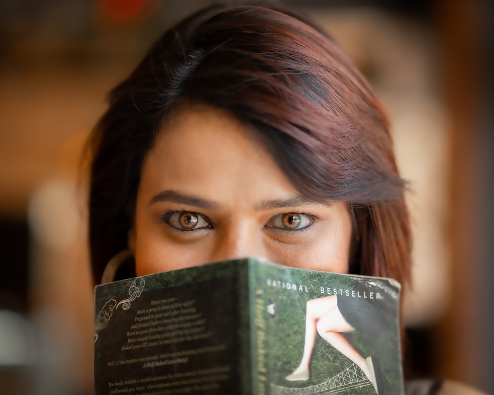 a woman holding a book up to her face