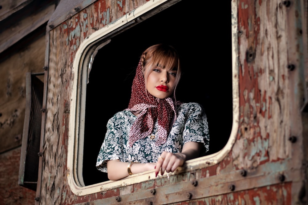 a woman with a scarf on looking out of a window