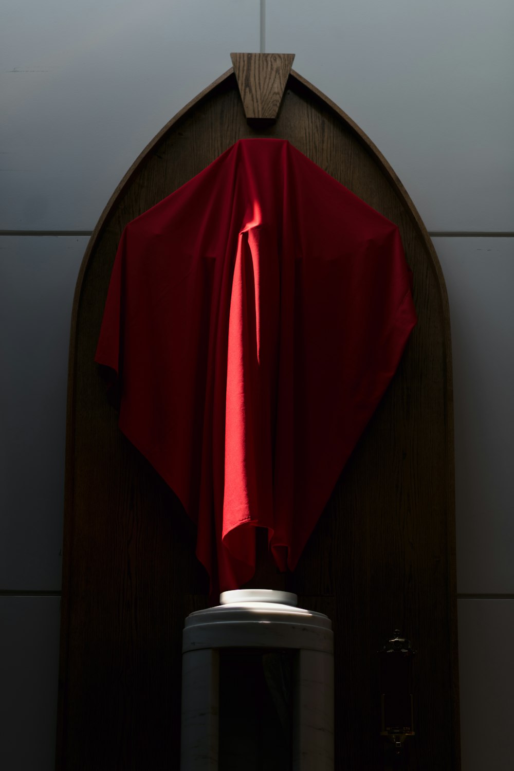 a red cloth draped over a cross on a wall