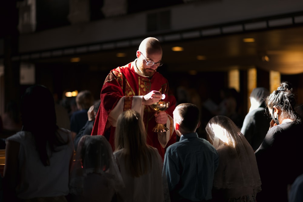 a man in a priest's outfit standing in front of a group of people