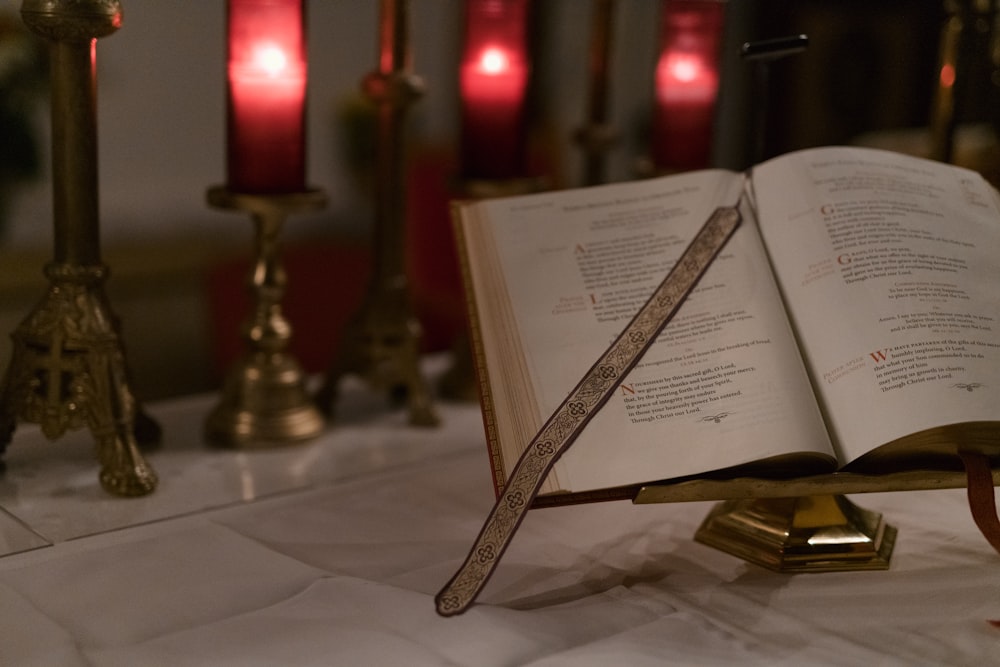an open book sitting on top of a table next to candles