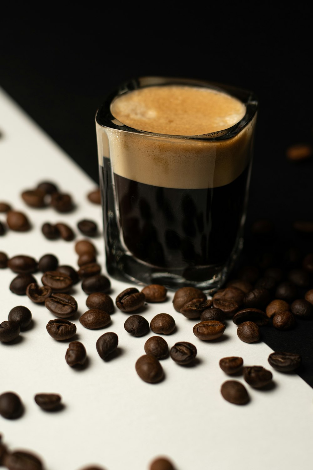 a shot glass filled with liquid surrounded by coffee beans