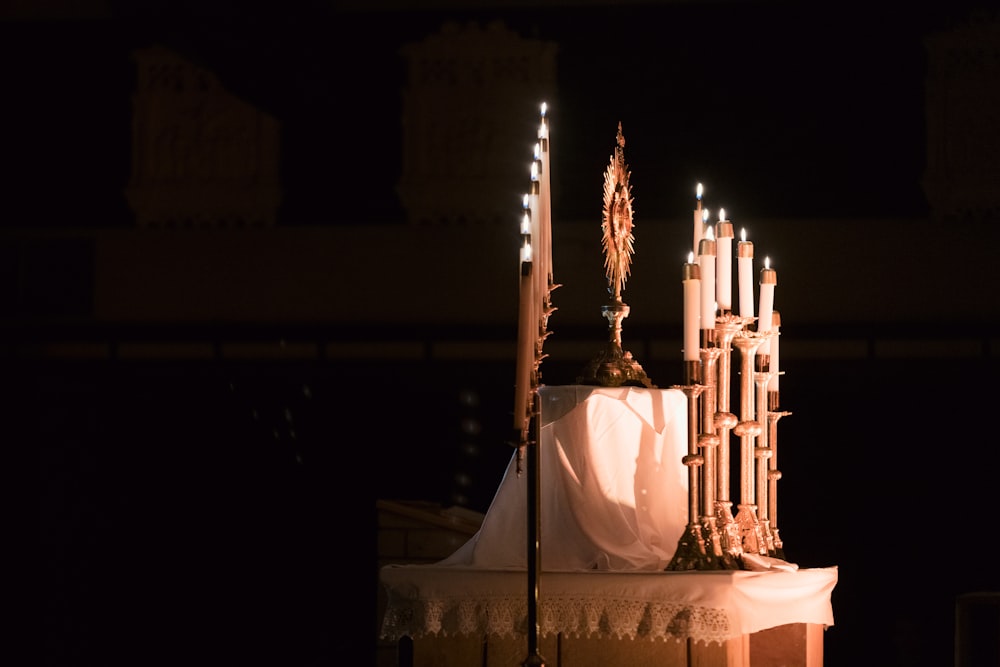 a church alter lit up with candles and a cloth draped over it
