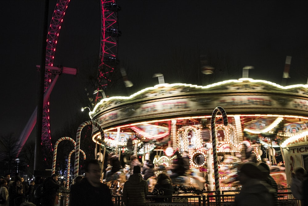 a merry go round at night with a ferris wheel in the background