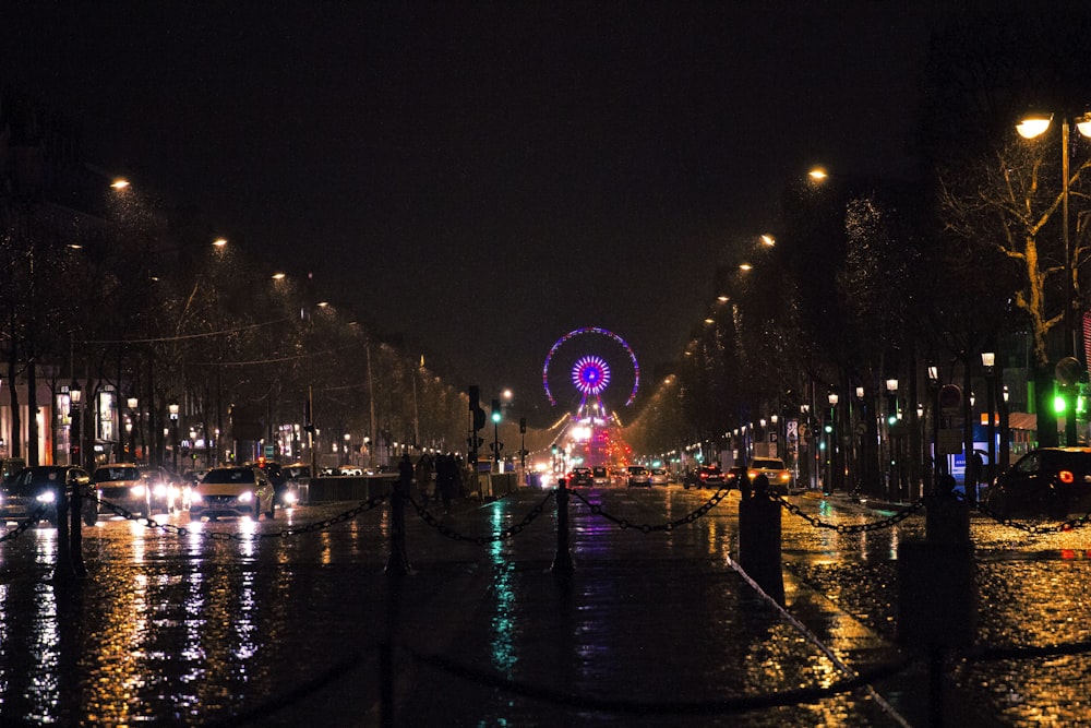 a city street at night with a ferris wheel in the background