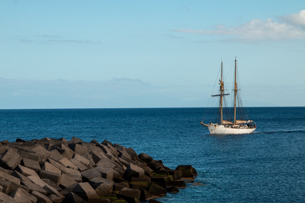 a sailboat in the ocean near a rocky shore