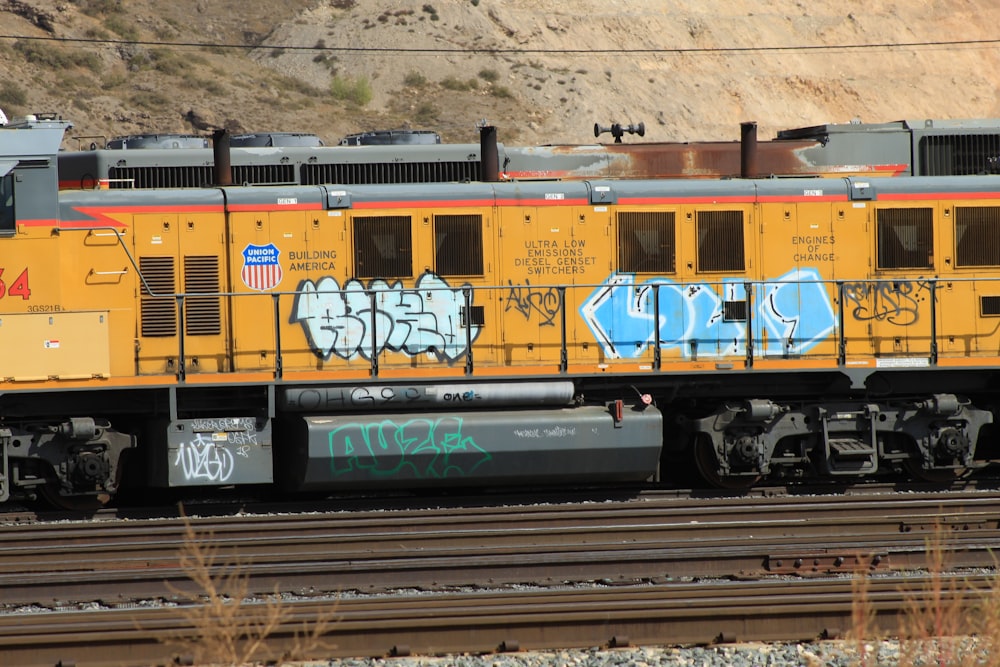 a yellow train with graffiti on the side of it