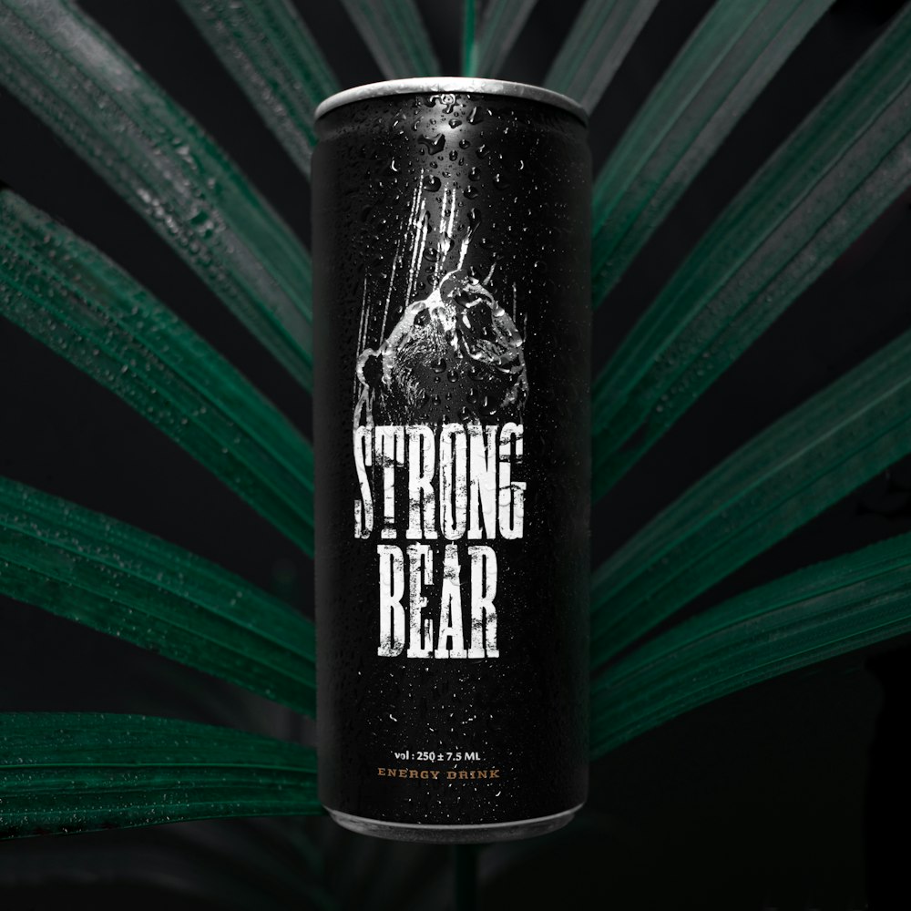a can of strong bear beer hanging from a palm leaf