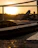Cinematic view of a premium boat anchored in turquoise waters with a sunset backdrop