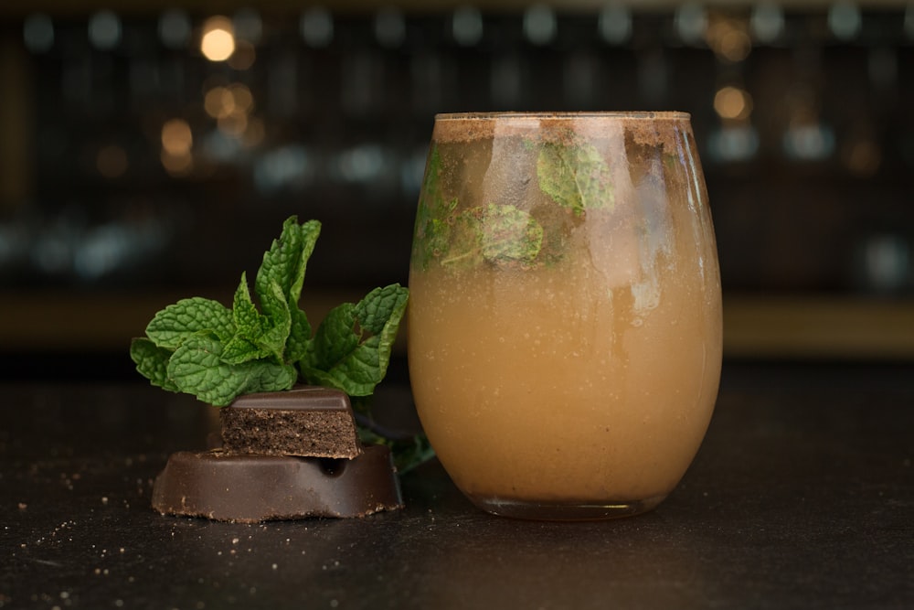 a glass filled with liquid next to a piece of chocolate