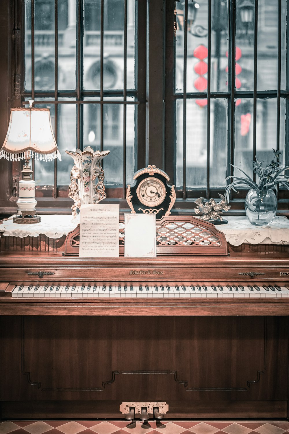 a piano sitting in front of a window next to a lamp