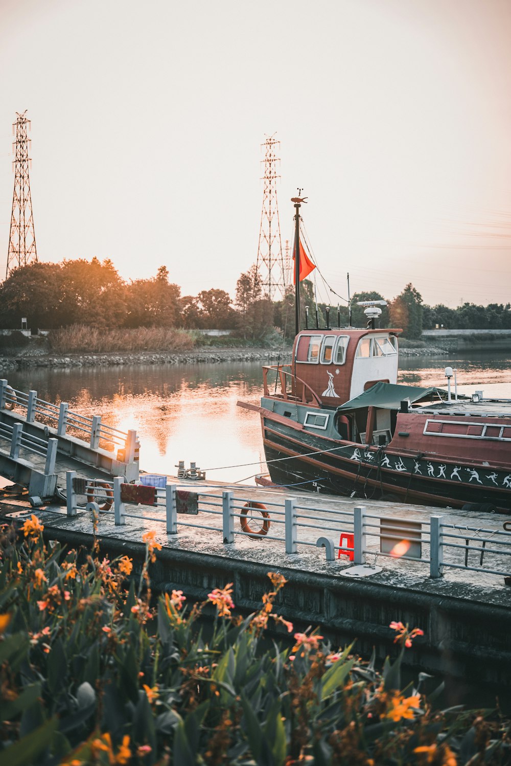 a boat docked at a pier with flowers in the foreground