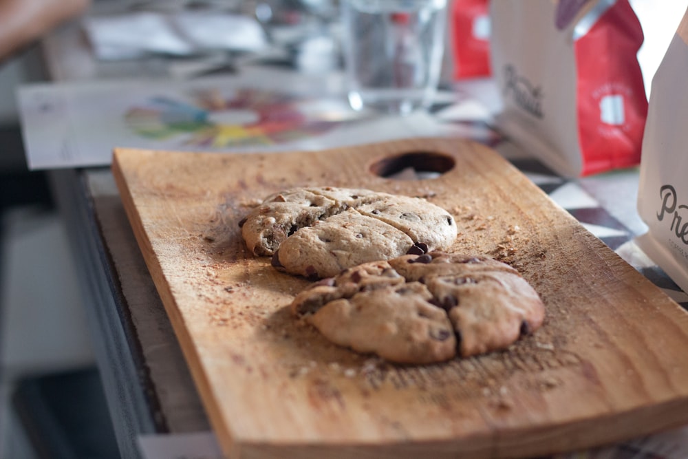 a wooden cutting board topped with cookies on top of a counter