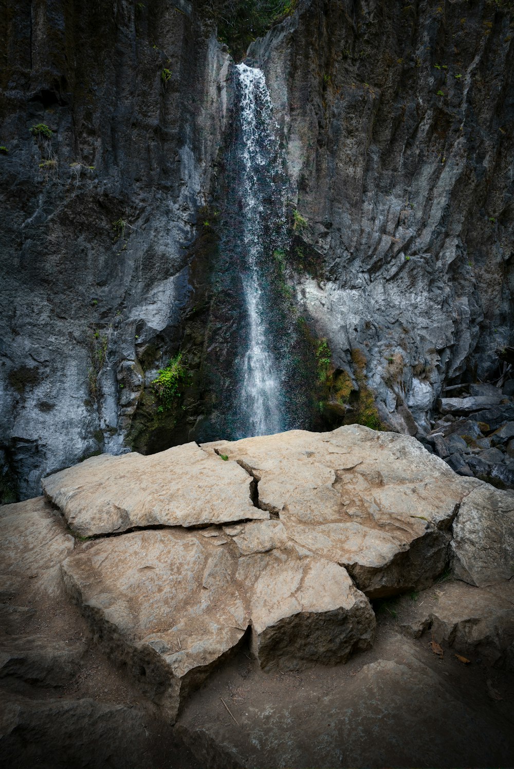 a large rock with a waterfall in the background