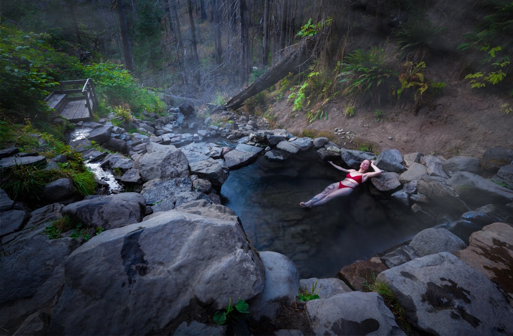 uma mulher deitada em uma rocha em uma piscina de água