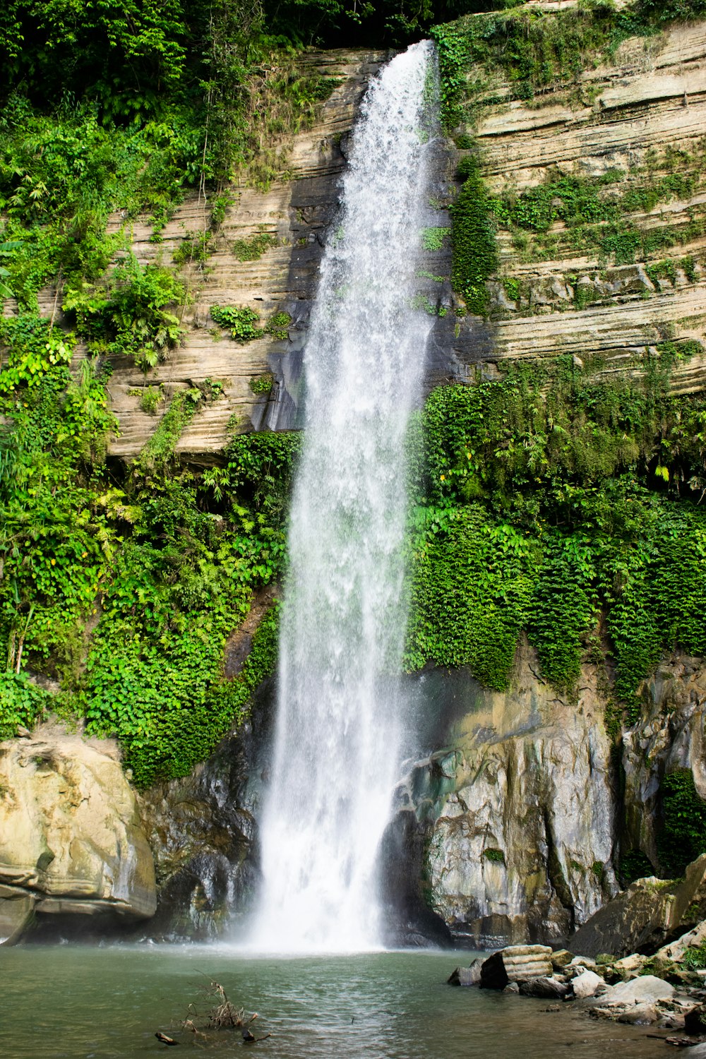 a large waterfall with a man standing in front of it