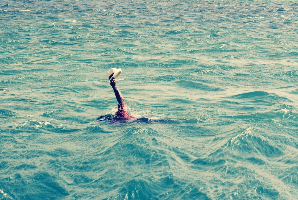 Eine Person, die mit einem Hut auf dem Kopf im Meer schwimmt