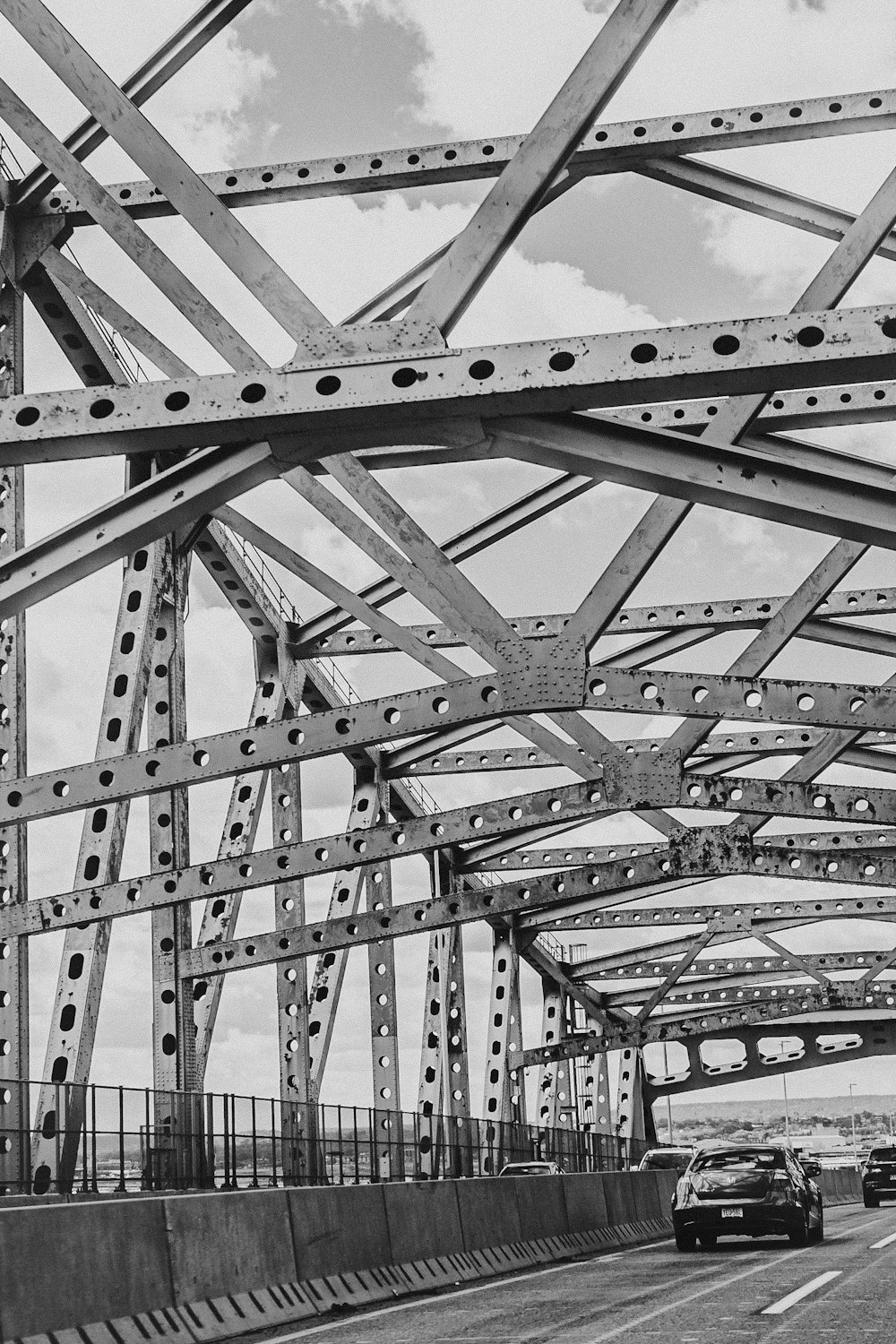 a black and white photo of cars driving on a bridge