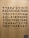A wooden surface displays a variety of black text symbols, numbers, and mathematical symbols arranged randomly, including plus, minus, division, and square root symbols. Among them are alphabets with accents and phrases like '1+1+1+1+1=6'. At the bottom, there is a smaller text with an asterisk indicating 'KADIN/WOMAN'.