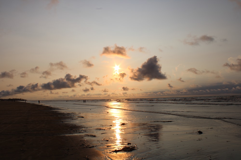 the sun is setting over the ocean on the beach