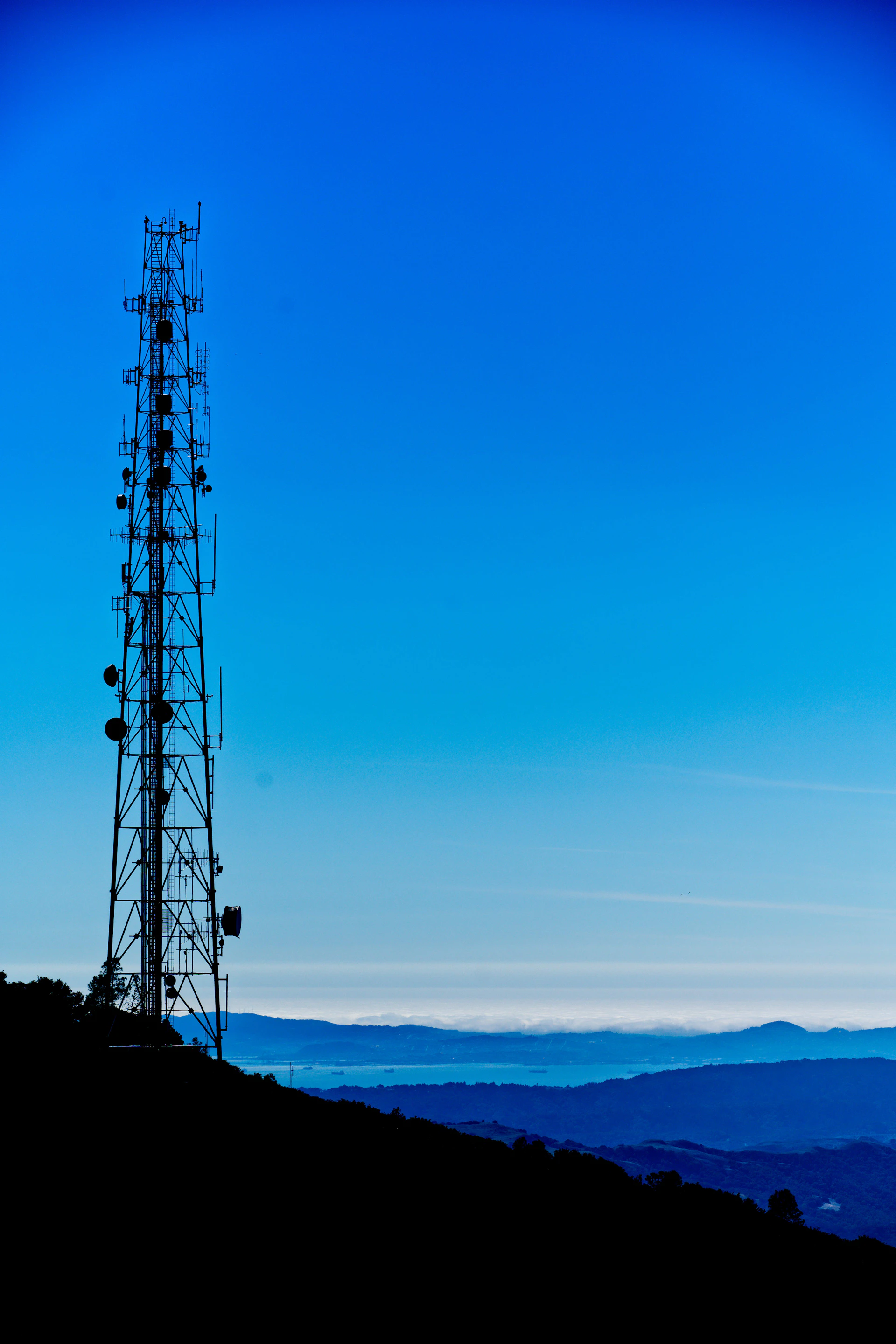 a radio tower on a hill with a blue sky in the background