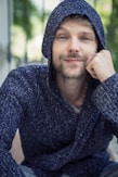 a man with a hoodie on sitting down