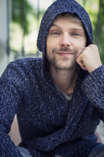 a man with a hoodie on sitting down