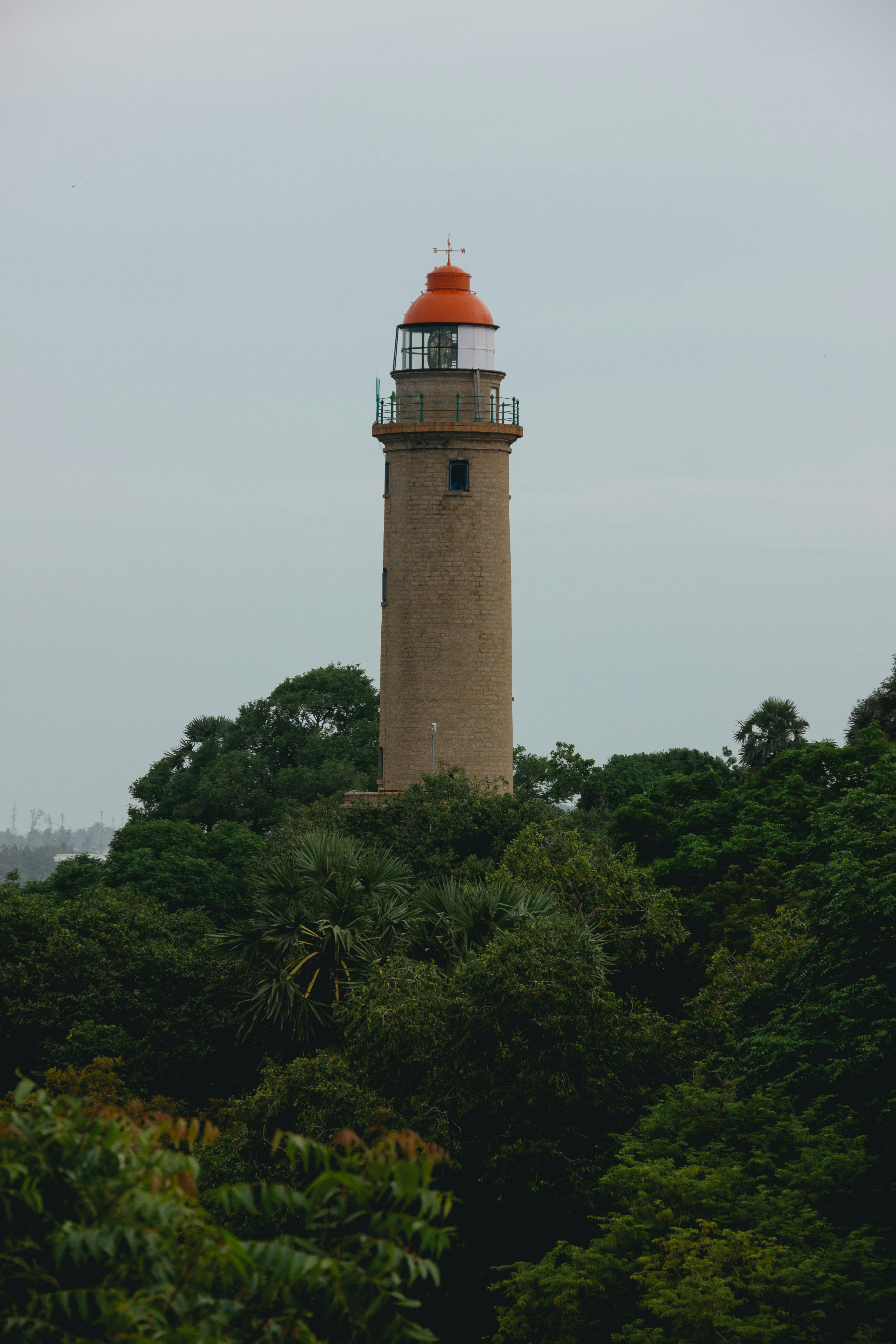 a tall light house surrounded by trees on a cloudy day