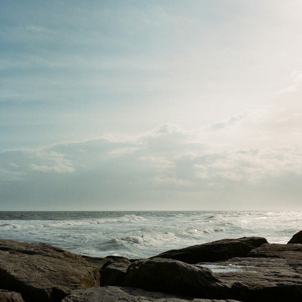 Eine Person, die auf einem Felsen in der Nähe des Ozeans sitzt