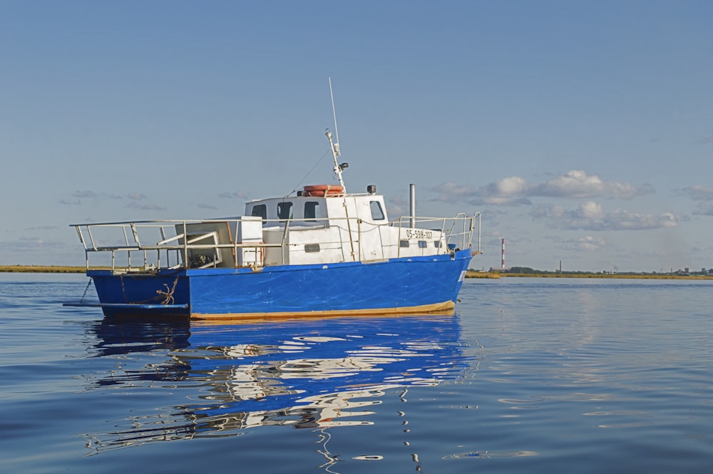 a blue and white boat floating on top of a body of water