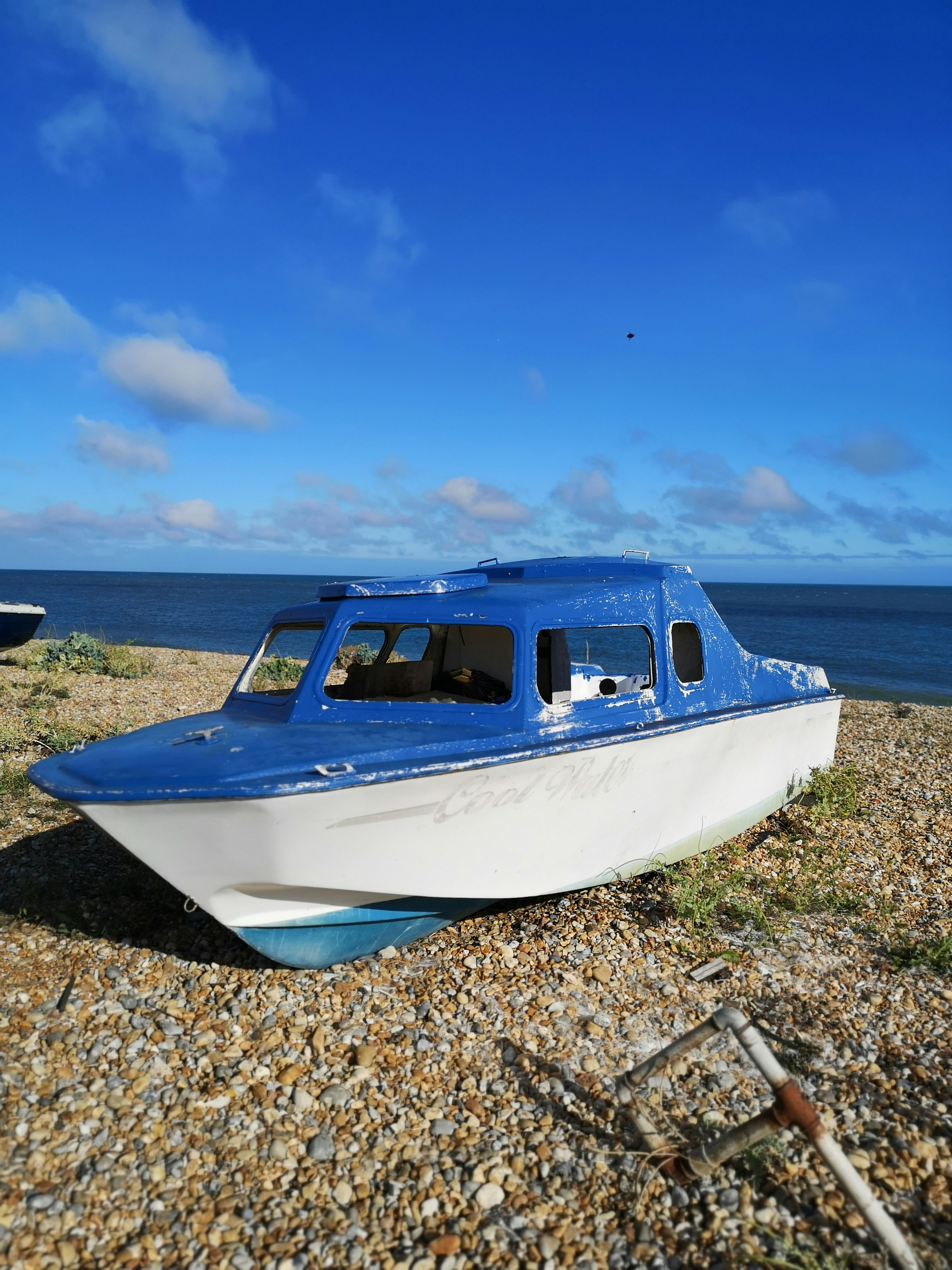 a blue and white boat sitting on top of a beach