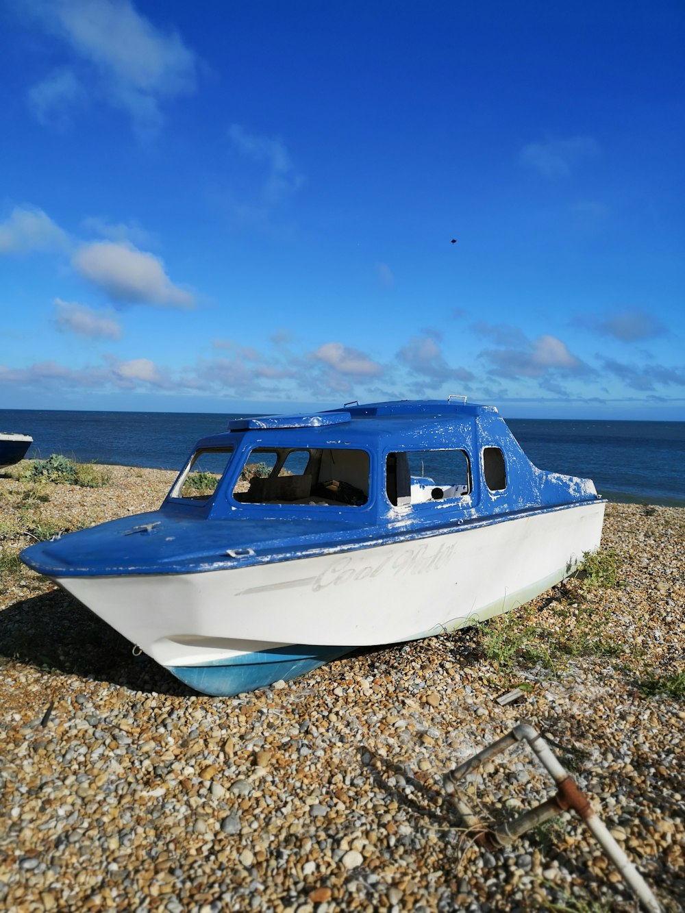 a blue and white boat sitting on top of a beach