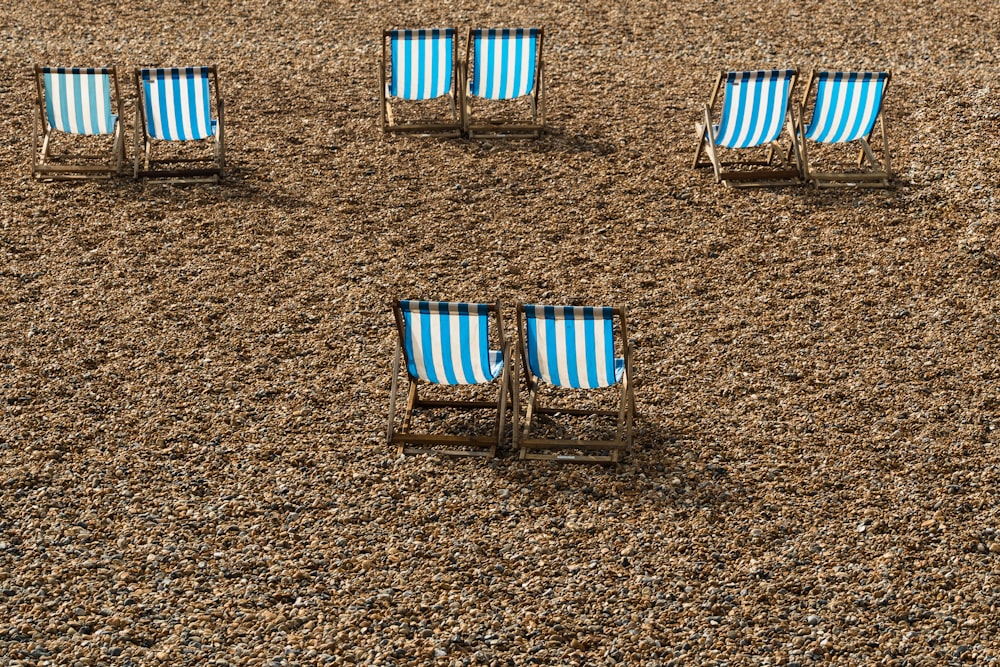 Un gruppo di sedie a sdraio seduti sulla cima di una spiaggia sabbiosa