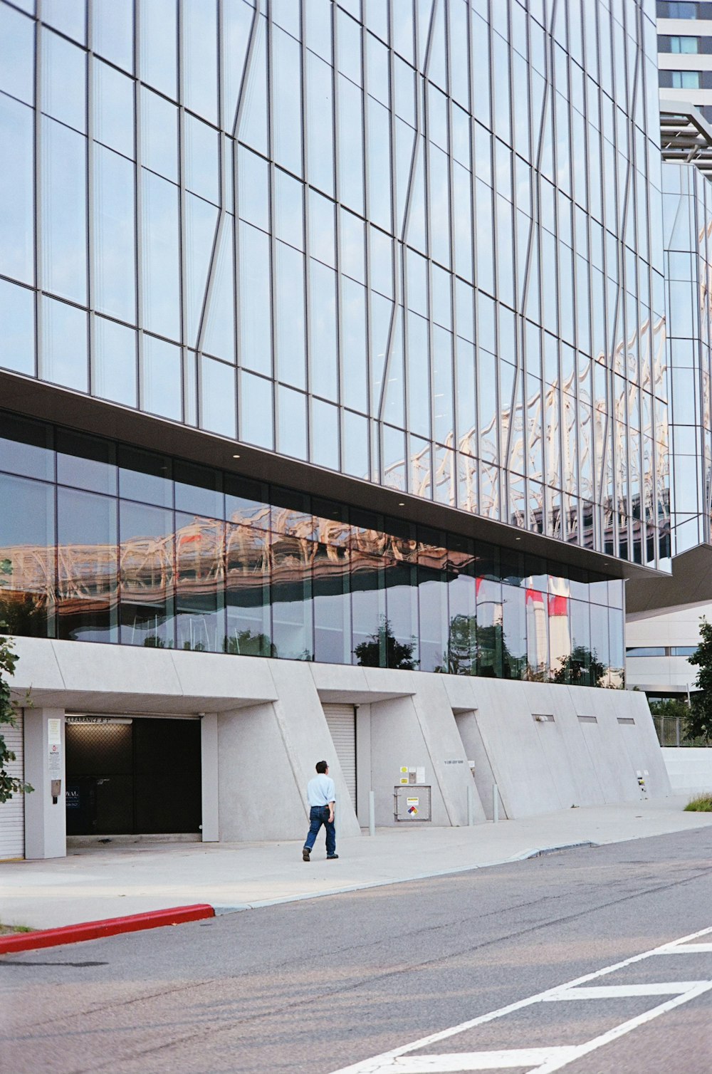 a man walking down a street past a tall building