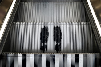 a couple of people riding down an escalator