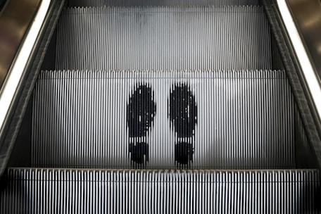 a couple of people riding down an escalator