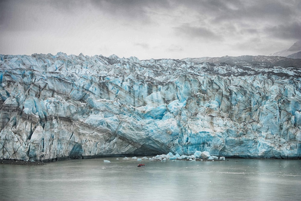 a large glacier with a boat in the water