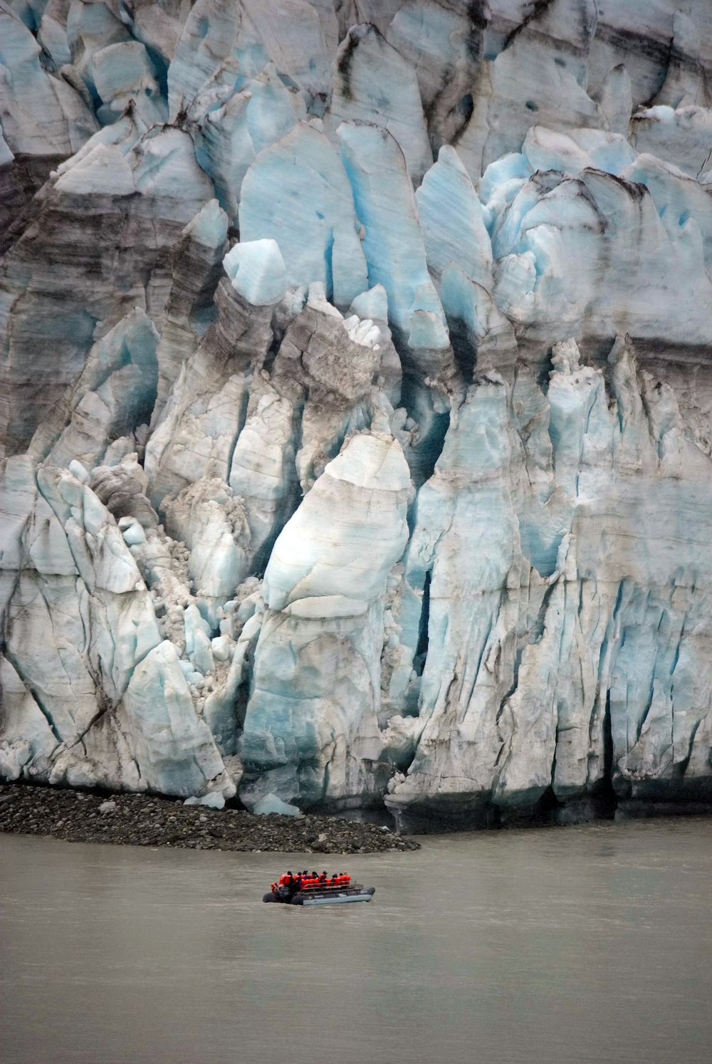 a group of people in a small boat in front of a glacier