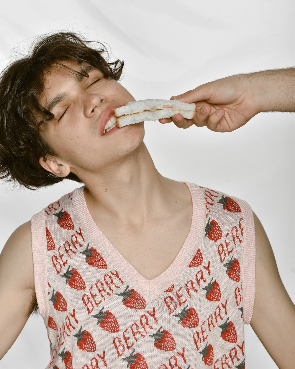 a man eating a donut while wearing a pink shirt