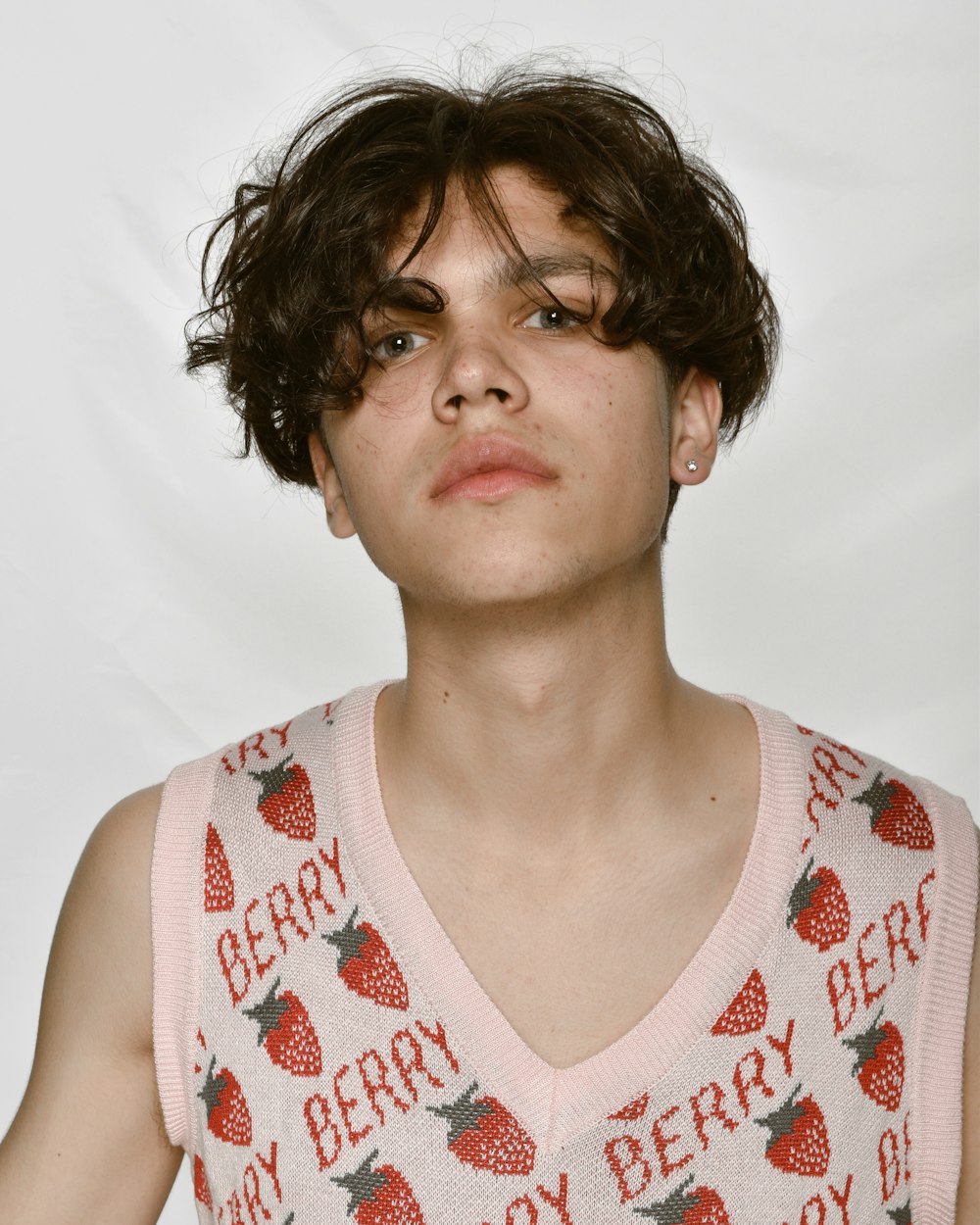 a young man wearing a pink shirt with strawberries on it