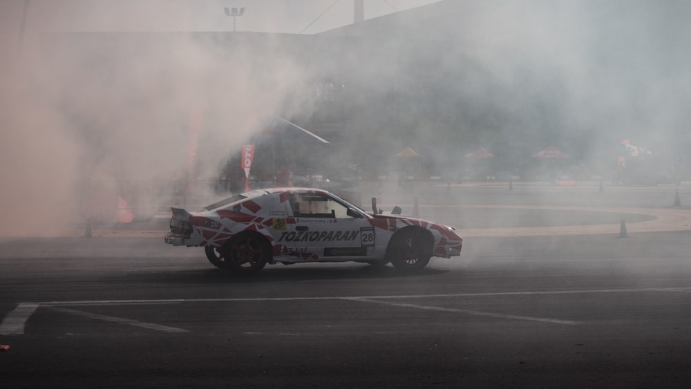 a car driving on a race track with smoke coming out of it