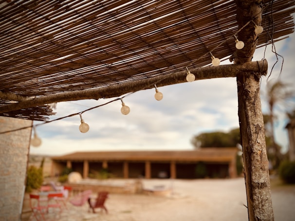 Outdoor decor featuring warm string lights wrapped around a rustic wooden pergola.