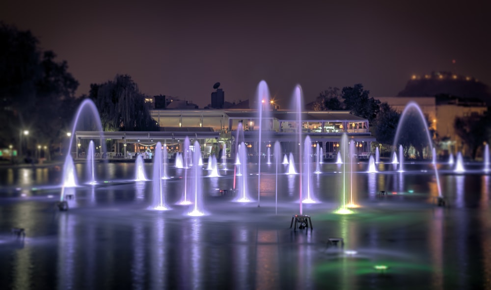 a night scene of a fountain with lights in the water