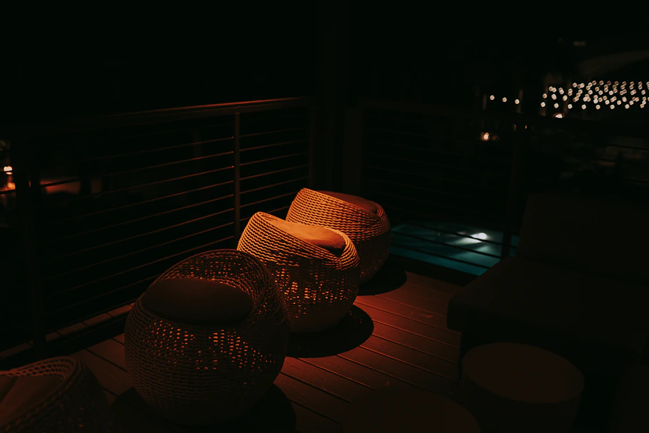 Cozy small apartment patio with swivel metal club chairs and a slatted composite pool ottoman under soft evening light