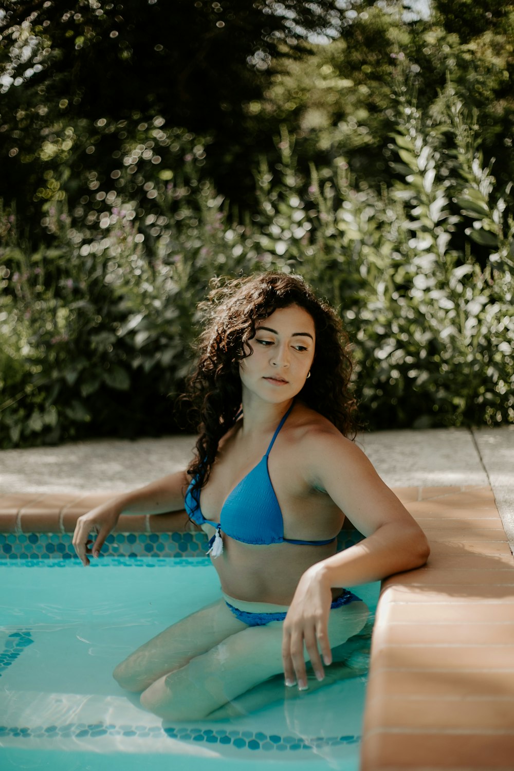 a woman in a blue bikini sitting in a pool