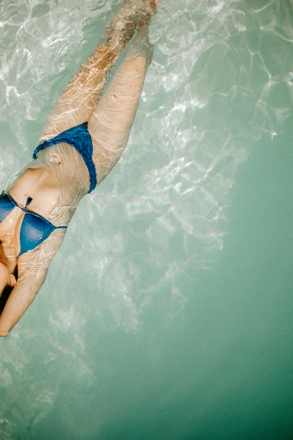 a woman in a blue bikini swimming in a pool