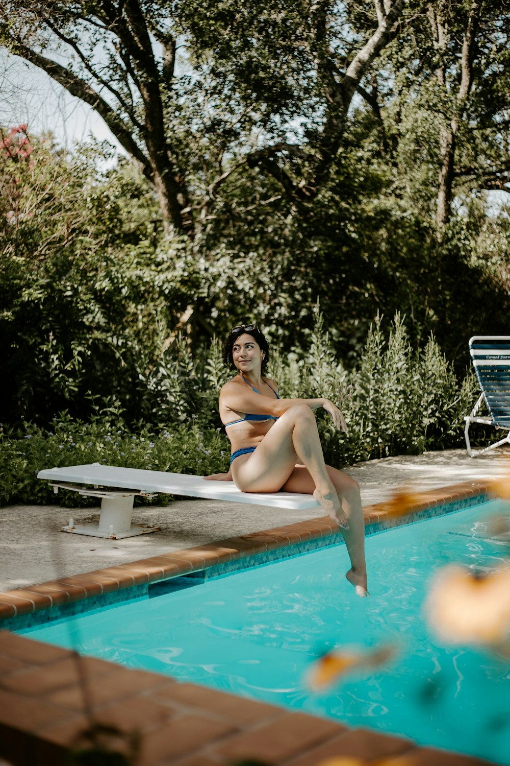 a woman sitting on a bench next to a swimming pool