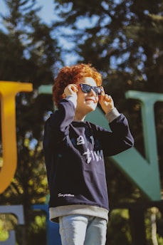 a young boy with red hair wearing sunglasses